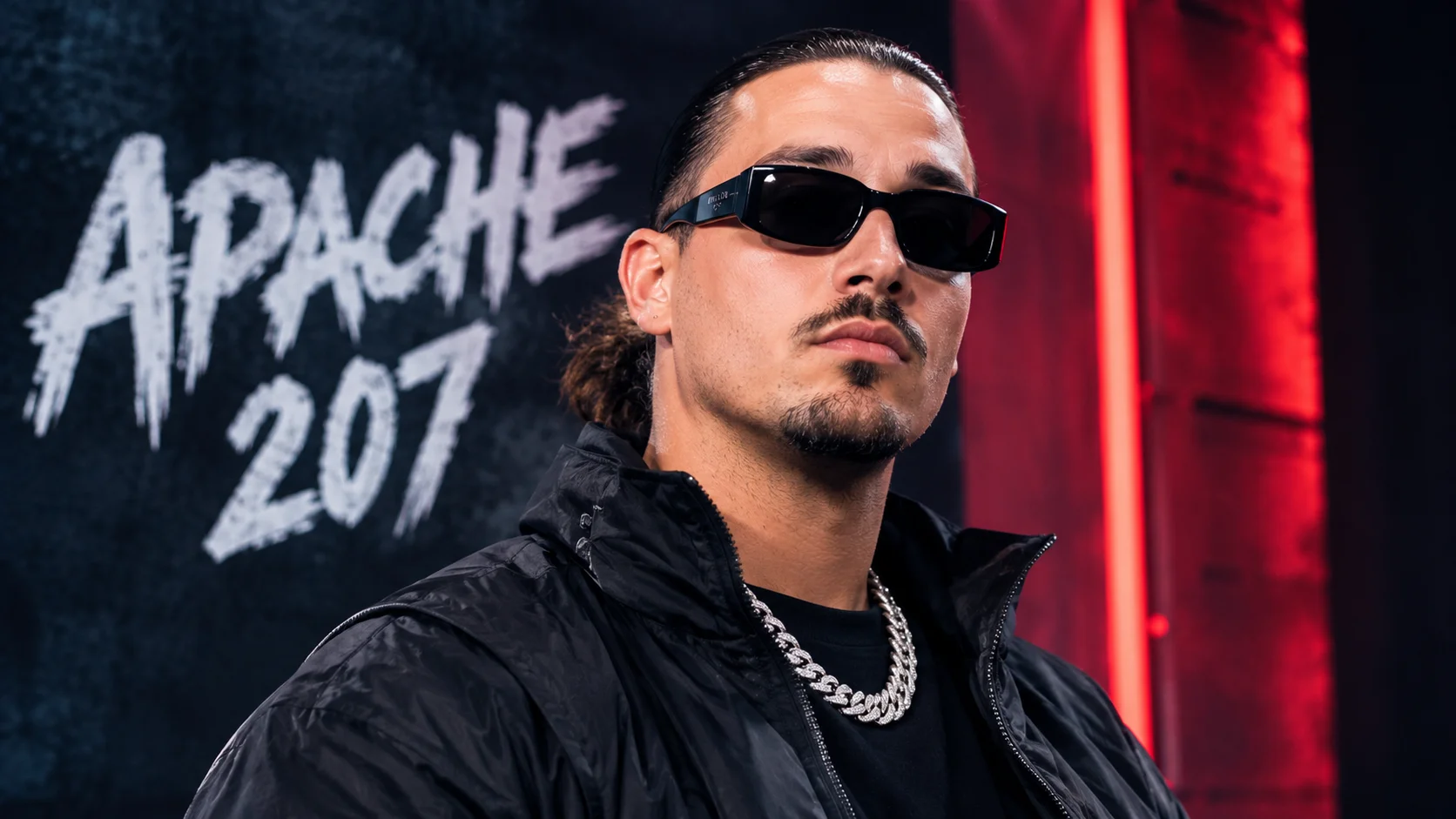 Apache 207 wearing sunglasses and performing in a dark urban setting